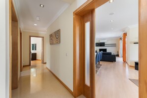 A spacious hallway with wooden flooring leading to a living area with a sofa and a television. - Villa 'Cadi' with Sea View, Wi-Fi and Air Conditioning (Albufeira)