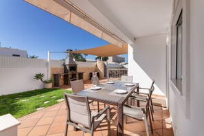 An outdoor patio with a table set for dining, surrounded by chairs, and a barbecue grill. - Villa 'Cadi' with Sea View, Wi-Fi and Air Conditioning (Albufeira)