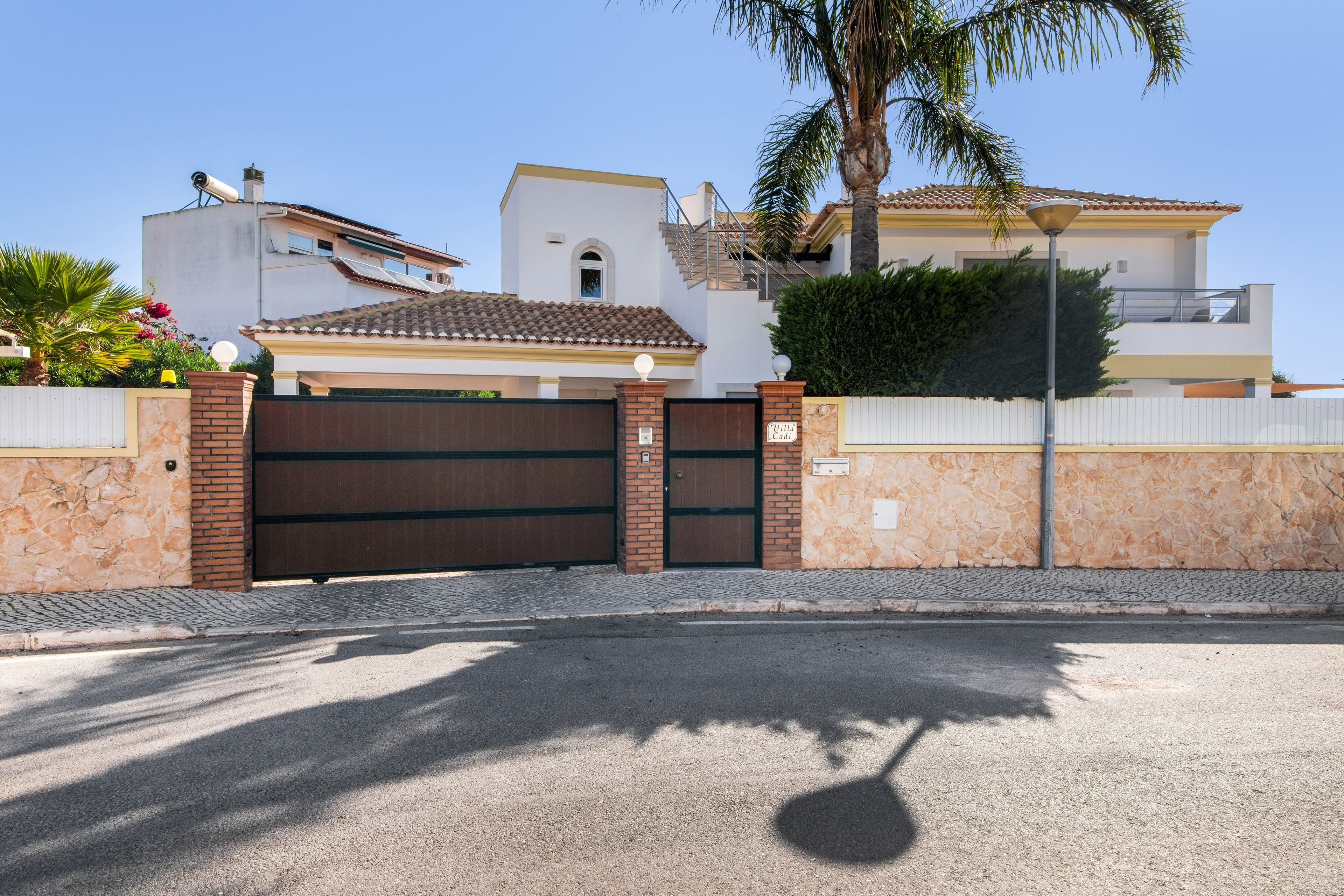 Una propiedad residencial cerrada con camino de entrada pavimentado, acceso mediante portón y césped bien cuidado.