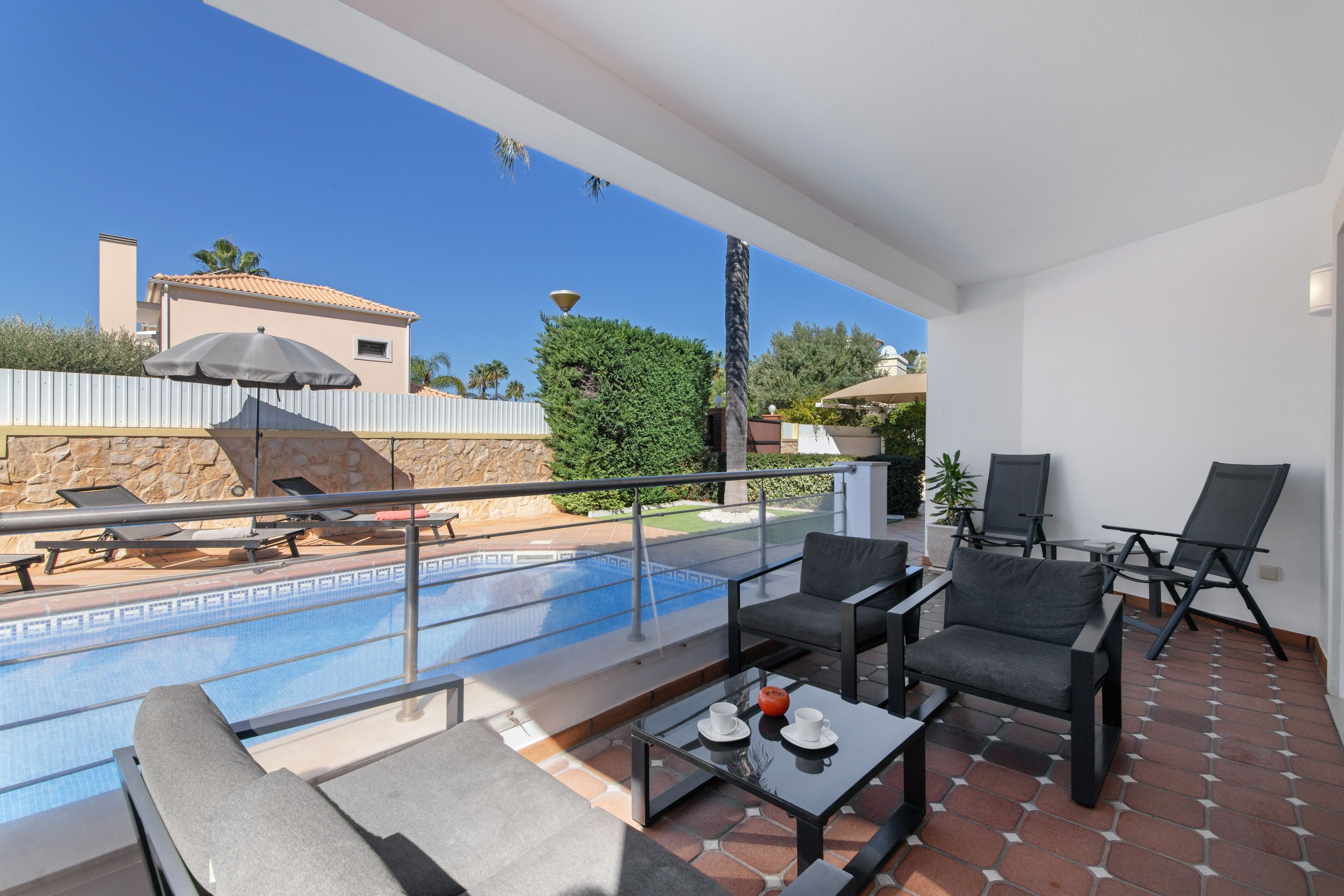 A modern outdoor lounge area with a pool, seating, and a view of the surrounding landscape.