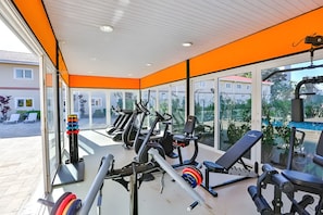 Ein Fitnessstudio mit Trainingsgeräten, großen Fenstern und Blick ins Freie.