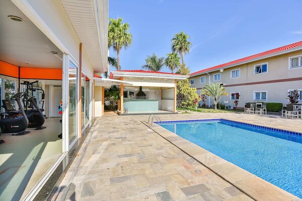 A swimming pool with a tiled deck, exercise equipment, and a covered area with a view of the pool. - Pet-Friendly Stay | Near Jundiaí Industrial Zone & Parque da Cidade (São Paulo)