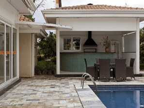 A pool area with a stone patio, a grill, and outdoor furniture. - Family-Friendly Stay | Free Breakfast & Pool | Near Jardim Botânico (São Paulo)
