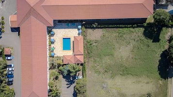 An aerial view of a building with a large parking lot, a swimming pool, and a grassy area.