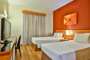 A hotel room with two single beds, a TV, a desk, and a large window with curtains. - Family-Friendly Stay | Free Breakfast & Pool | Near Jardim Botânico (São Paulo)