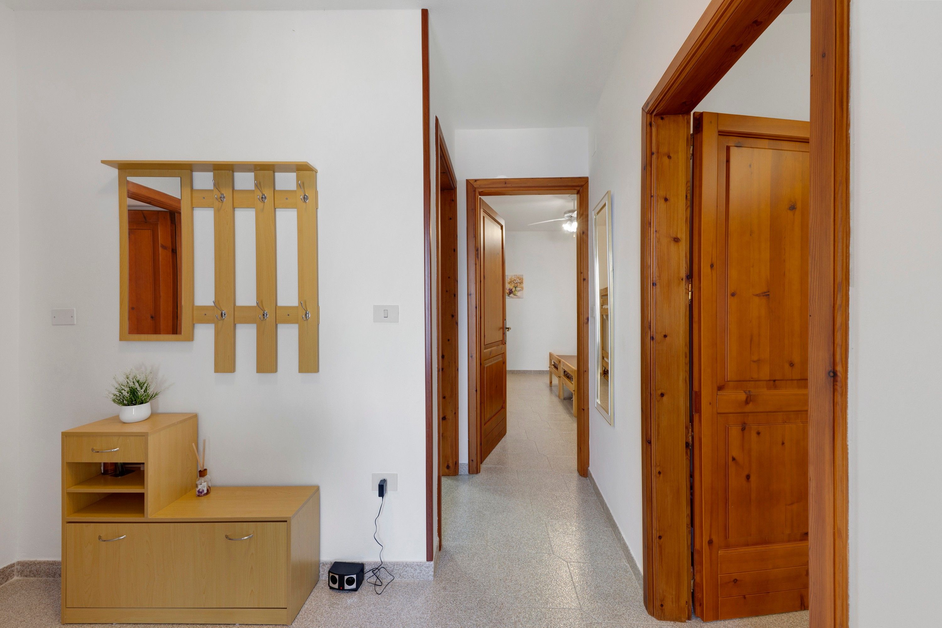 Ein Flur mit Holztüren, einem Spiegel, einem Holzschrank und einem kleinen Tisch mit einer Pflanze.