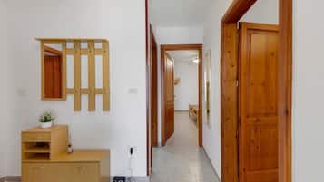 A hallway with wooden doors, a mirror, a wooden cabinet, and a small table with a plant.