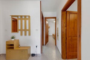 A hallway with wooden doors, a mirror, a wooden cabinet, and a small table with a plant.