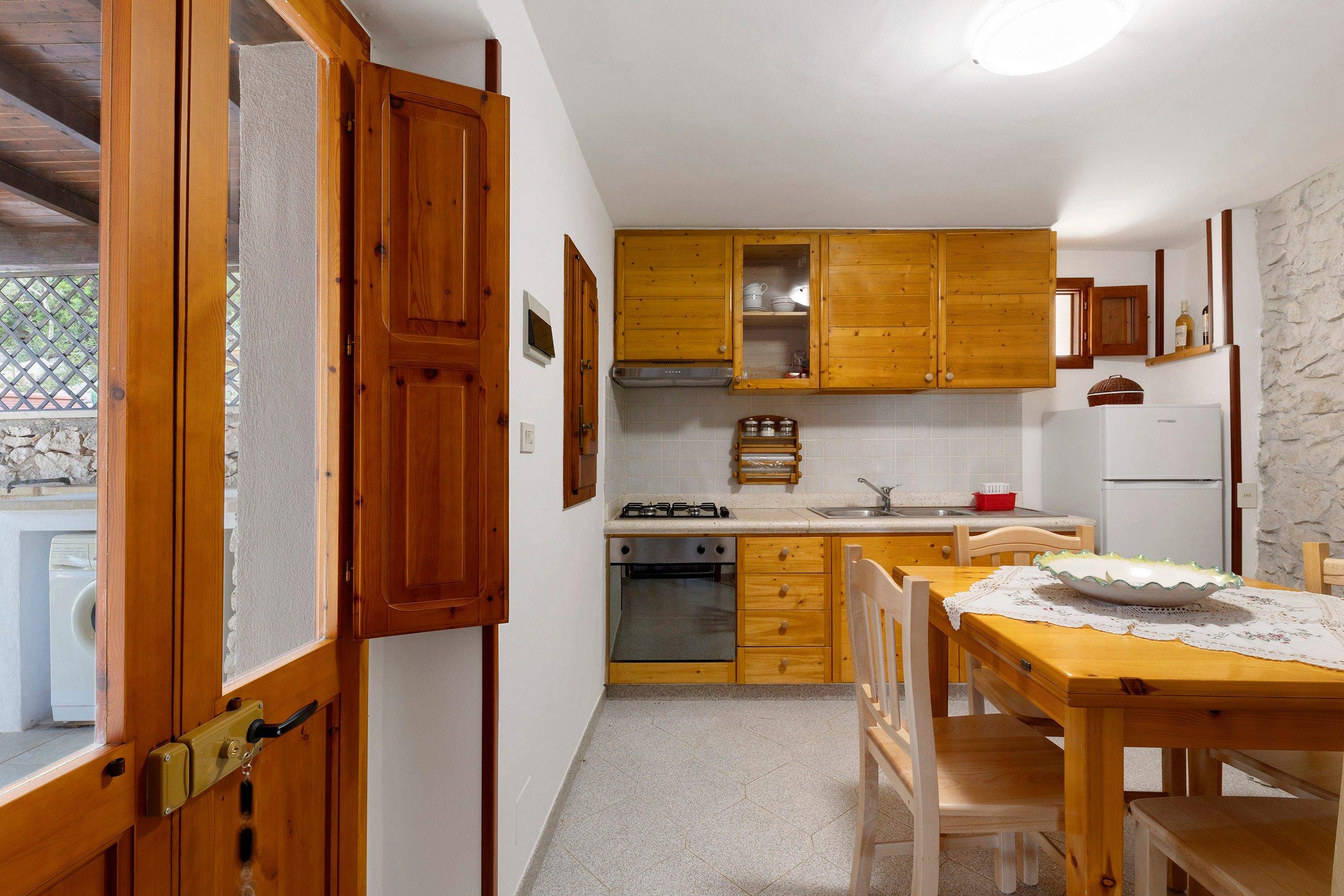 A kitchen with wooden cabinets, a stove, a sink, and a dining table with chairs.