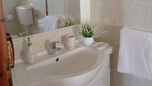 Ein Badezimmer mit einem großen Waschbecken, einem Spiegel, einer Toilette und einem Handtuchhalter.