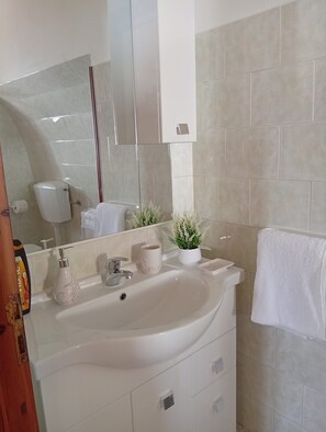 Une salle de bain avec un grand lavabo, un miroir, des toilettes et un porte-serviettes.