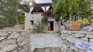 A stone-walled entrance with a wooden door and steps leading to a villa.