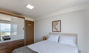 Un dormitorio con cama, armario, espejo y un cuadro en la pared.