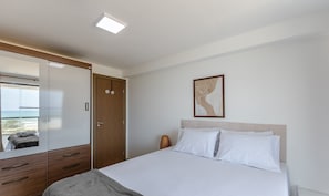 Un dormitorio con cama, armario, espejo y un cuadro en la pared.
