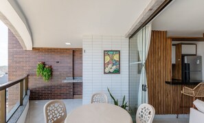 Uma varanda moderna com parede de tijolos, porta de vidro e área de refeições com mesa e cadeiras redondas.