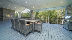En udendørs terrasse med et bord, stole, en stenspir og en grill.
