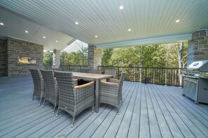 Een terras buiten met een tafel, stoelen, een stenen open haard en een barbecue.