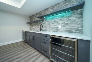 A modern kitchen with a stone backsplash, stainless steel appliances, and a skylight. - Executive Cottage on Lakeview HotTub Firepit Sauna Nearby Walking Nature Trails (Lambton Shores)