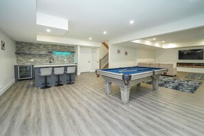 Un salon moderne avec une table de billard, un coin bar et une cheminée.