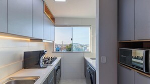 A modern kitchen with a built-in oven, a coffee machine, and a window offering a city view. - Sea View Apartment 300m From the Beach Mmd0403 (Ilhéus)