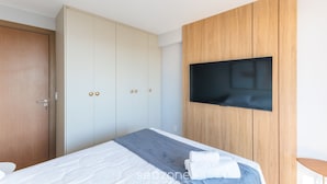 A modern bedroom with a bed, a wardrobe, and a mounted TV. - Sea View Apartment 300m From the Beach Mmd0403 (Ilhéus)
