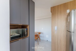 Una cocina moderna con microondas integrado, un refrigerador y un armario de madera.