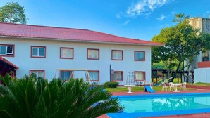 A hotel with a swimming pool, a grassy area, and a building with a red roof. - Peaceful, Airy Unit in a Prime Location Near Belém’s Highlights + Pool Access (Pará)
