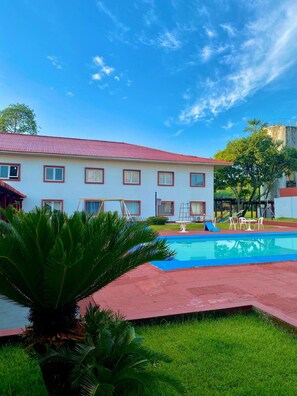 A hotel with a swimming pool, a grassy area, and a building with a red roof. - Peaceful, Airy Unit in a Prime Location Near Belém’s Highlights + Pool Access (Pará)