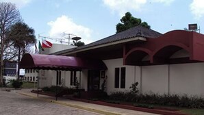 Un edificio con un toldo rojo, una bandera y un área de entrada con baldosas.