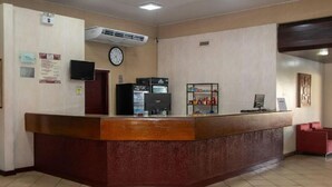 Un espace d’accueil comprenant un comptoir de réception en bois, une horloge, un réfrigérateur et une machine à café.