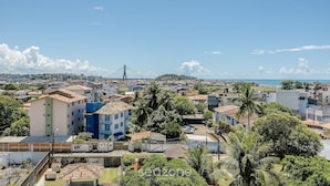 A coastal cityscape with a prominent bridge, residential buildings, and lush greenery.