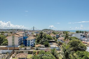 Un paisaje urbano costero con un puente destacado, edificios residenciales y abundante vegetación.