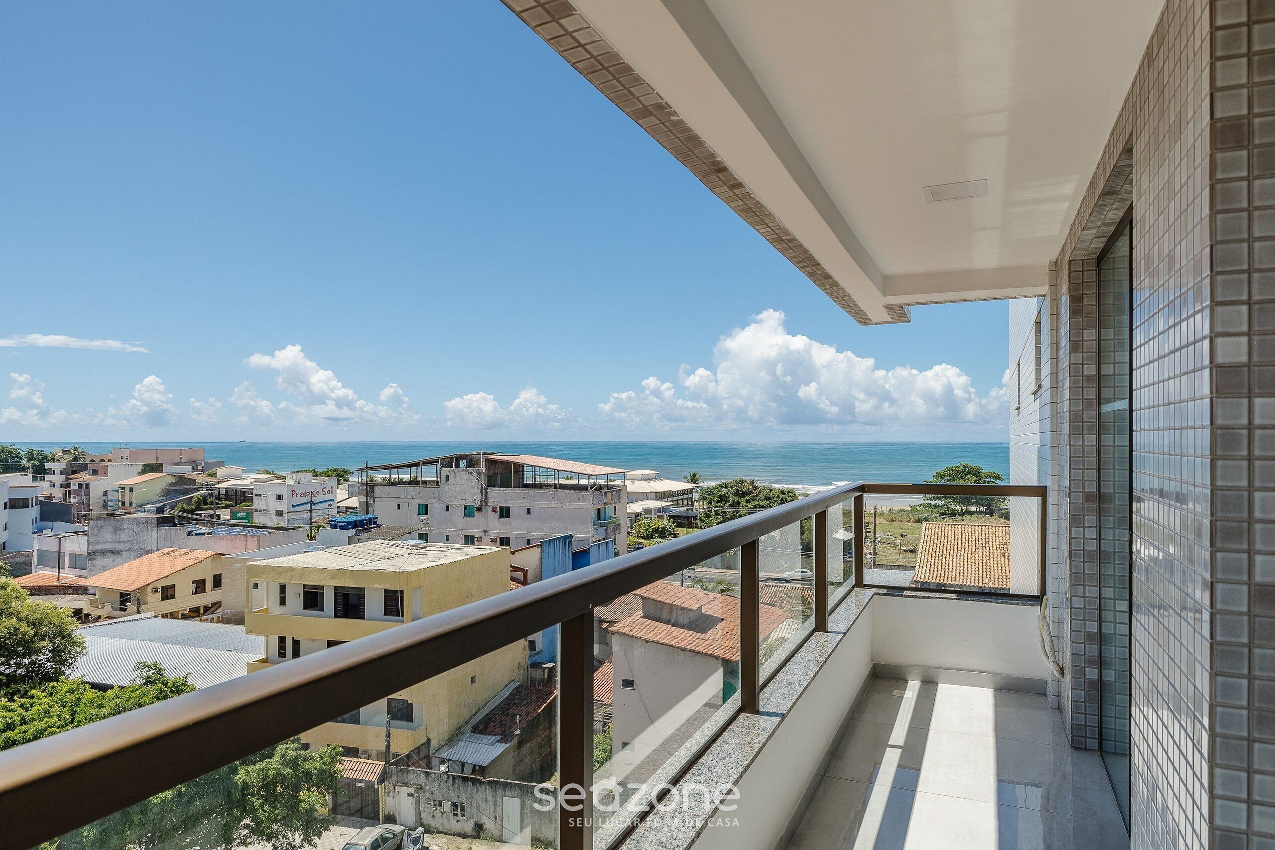 Un balcón con vistas a una ciudad costera, incluyendo edificios y el mar.