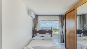 A hotel room with a bed, a view of the sea, and a sliding door. - Apt With Balcony and sea View in Ilheus - Mmd0503 (Ilhéus)