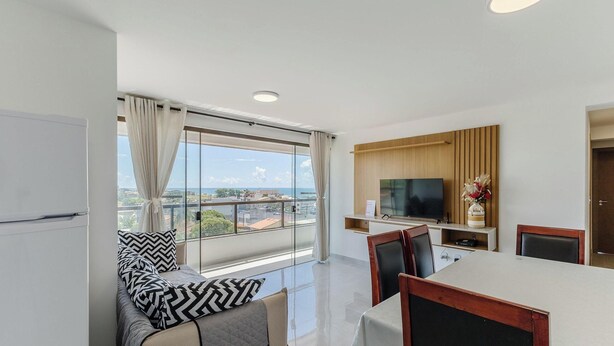 A modern living room with a sofa, a dining table, and a TV. - Apt With Balcony and sea View in Ilheus - Mmd0503 (Ilhéus)