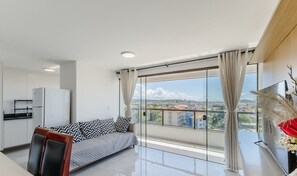 Una sala de estar moderna con un sofá, televisor y una zona de cocina.