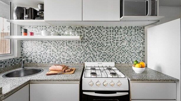 Una cocina con estufa a gas, microondas y salpicadero de azulejos.