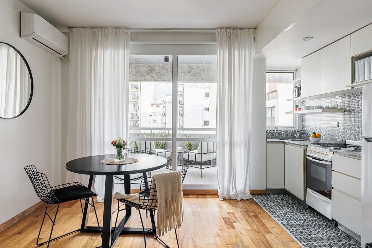A modern kitchen with white cabinets, a tiled backsplash, and a dining area with a round table and chairs.