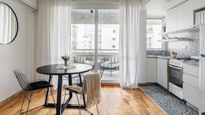 Una cocina moderna con armarios blancos, salpicadero de azulejos y un comedor con mesa y sillas redondas.