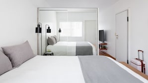 Una habitación de hotel moderna con cama, mesitas de noche, televisor y armario.