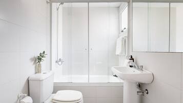 Un baño moderno con inodoro, lavamanos y ducha.