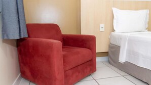 Ein roter Sessel in einem Zimmer mit einem Bett und einer Holzwand.