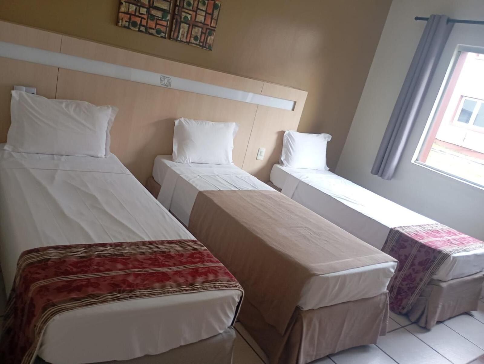 Ein Hotelzimmer mit zwei Einzelbetten, einem kleinen Tisch und einem Fenster mit Vorhängen.