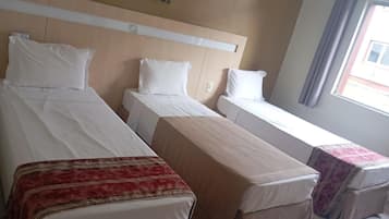 Ein Hotelzimmer mit zwei Einzelbetten, einem kleinen Tisch und einem Fenster mit Vorhängen.