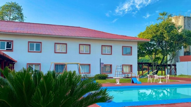 Un hôtel doté d’une piscine, d’une pelouse et d’un bâtiment surmonté d’un toit rouge.
