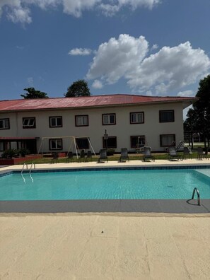A pool area with a building in the background. - Enjoy a Relaxing Stay in a Serene Room w/ Easy Access to Outdoor Pool & Lake (Pará)
