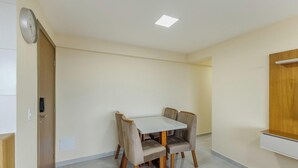 A room with a dining table and four chairs, a clock on the wall, and a recessed ceiling light. - Stay Near sea w/ Pool & Balcony Mmd0604 (Ilhéus)