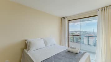 A bedroom with a bed, a view of the city, and a skylight.