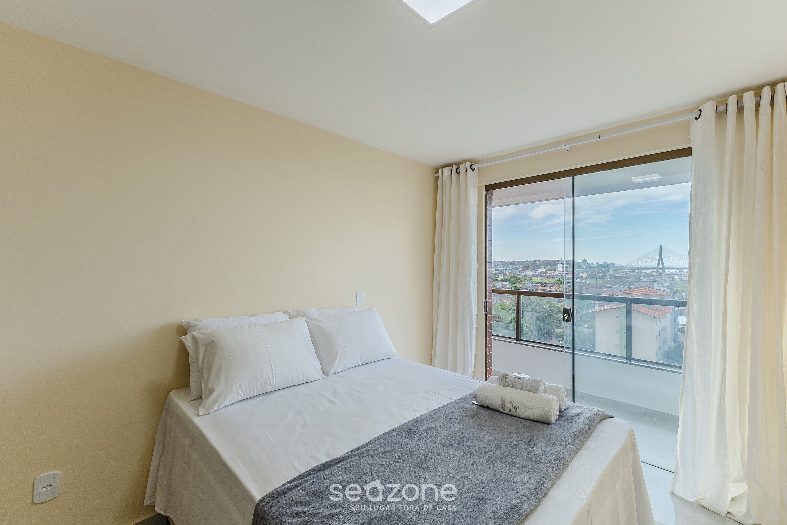 A bedroom with a bed, a view of the city, and a skylight.