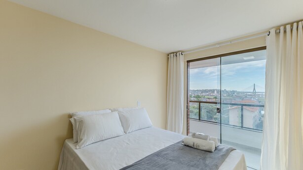 A bedroom with a bed, a view of the city, and a skylight. - Stay Near sea w/ Pool & Balcony Mmd0604 (Ilhéus)